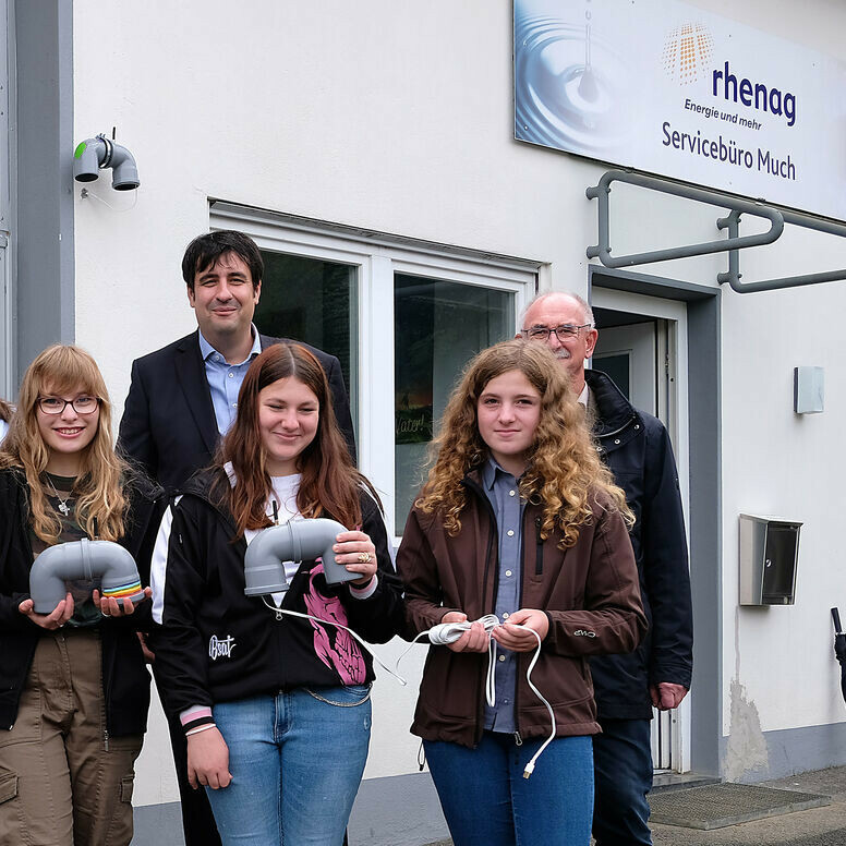 Schüler stehen mit Rohren vor dem rhenag-Servicebüro in Much.