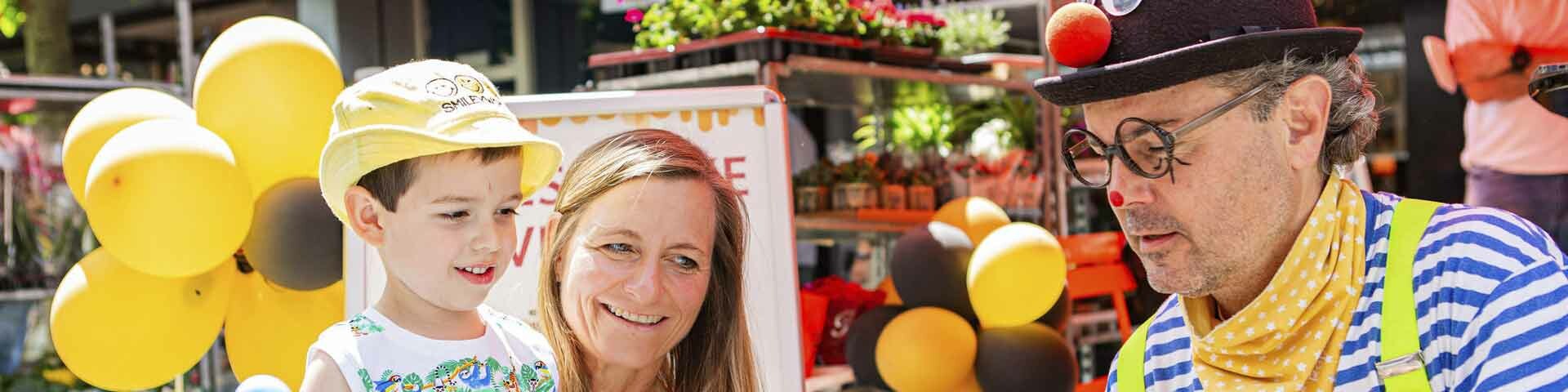 Mutter mit ihrem Sohn und einem Clown auf einem Straßenfest