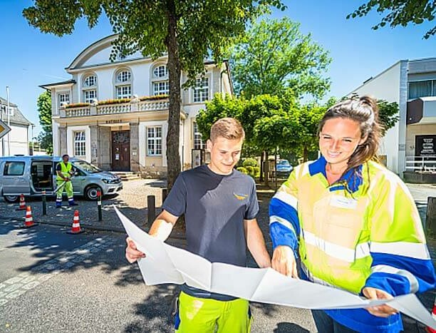 Mann und Frau in Arbeitsmontur schauen sich einen Plan an.