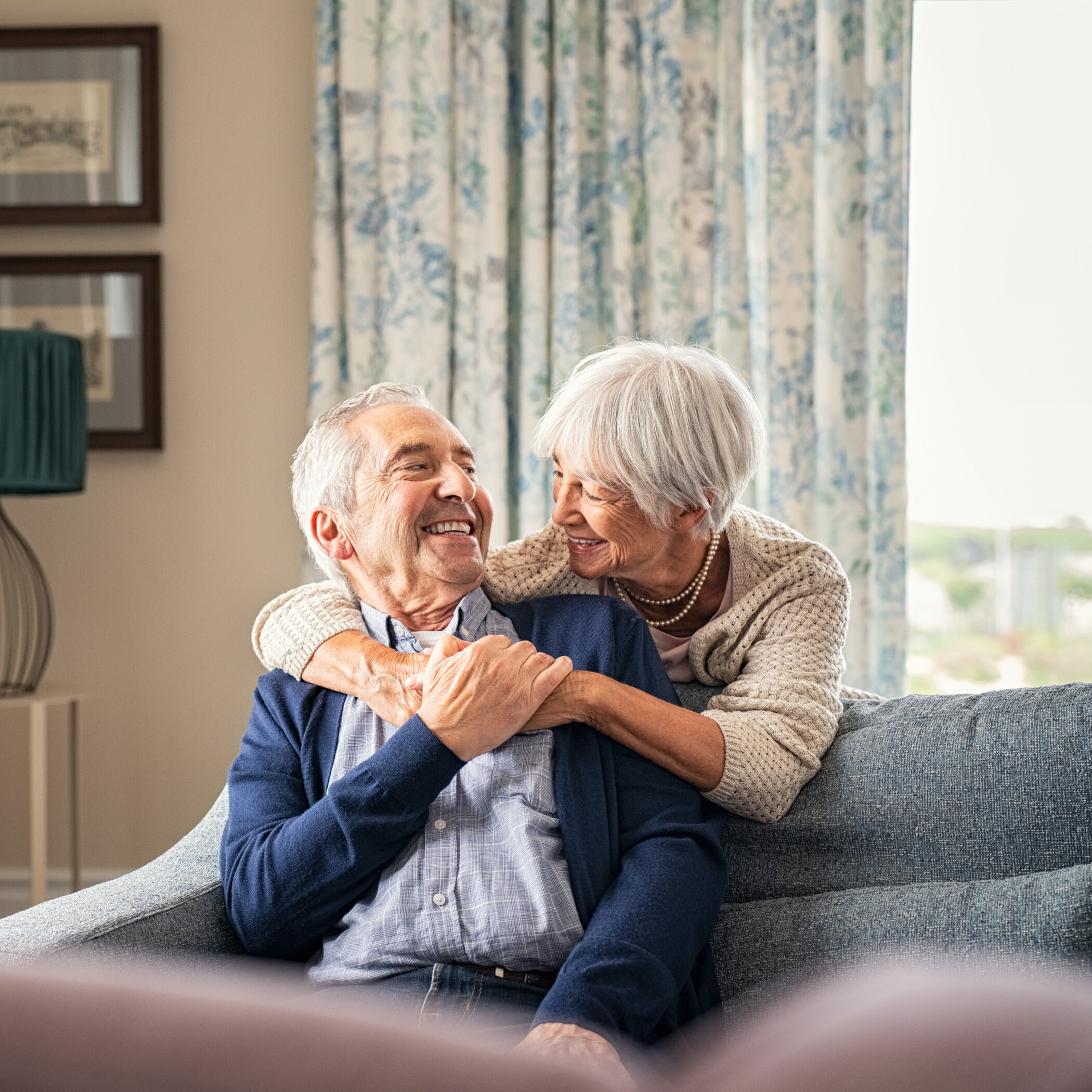 Ein älteres Paar umarmt sich zuhause auf dem Sofa.
