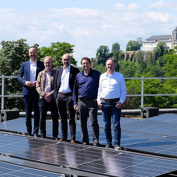 Fünf Personen stehen auf dem Dach des Oktopus Bads in Siegburg. Das Dach ist belegt mit Photovoltaikmodulen.