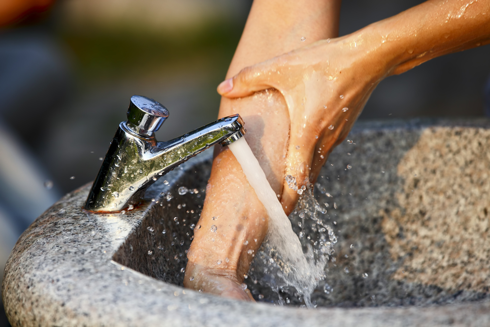 Händewaschen unter fließend Wasser im Waschbecken.