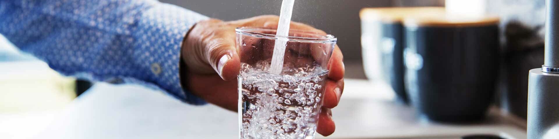 Wasser aus dem Wasserhahn fließt in ein Glas.