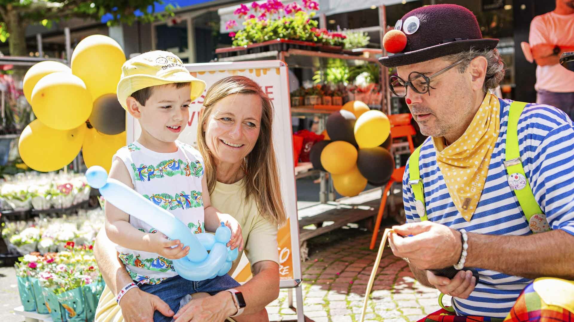 Mutter mit ihrem Sohn und einem Clown auf einem Straßenfest