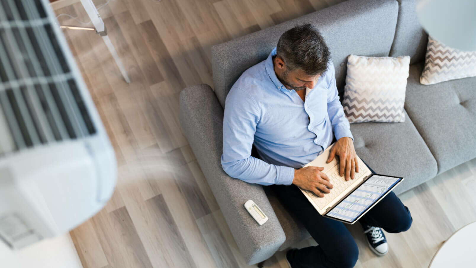 Mann sitzt mit Laptop auf dem Sofa