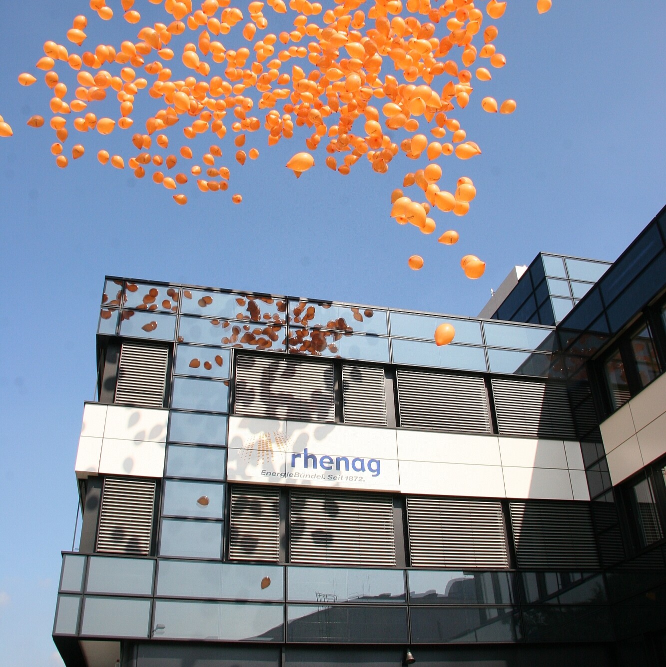 Orangene Luftballons fliegen über das rhenag-Gebäude in Siegburg.