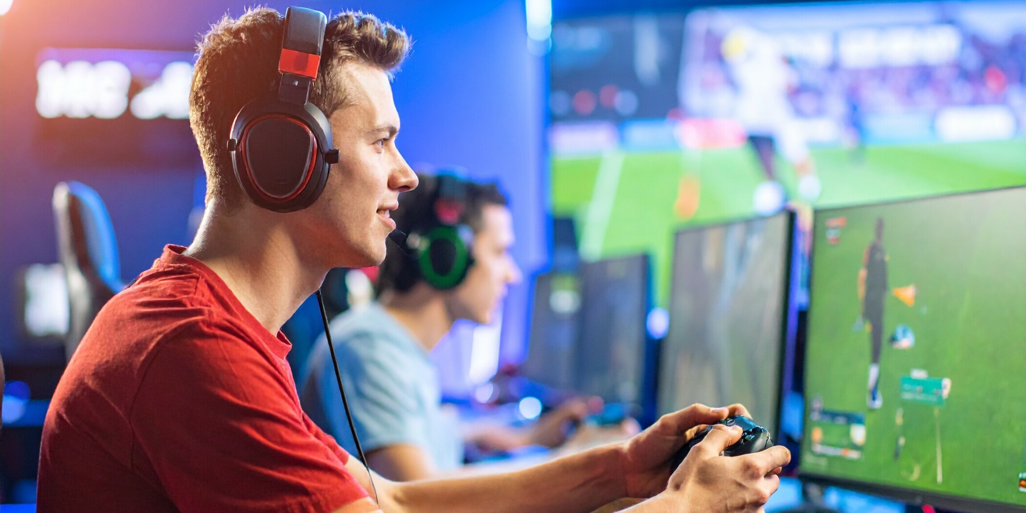 Ein junger Mann mit Kopfhörern spielt auf einem eSports-Event mit Controller in der Hand.