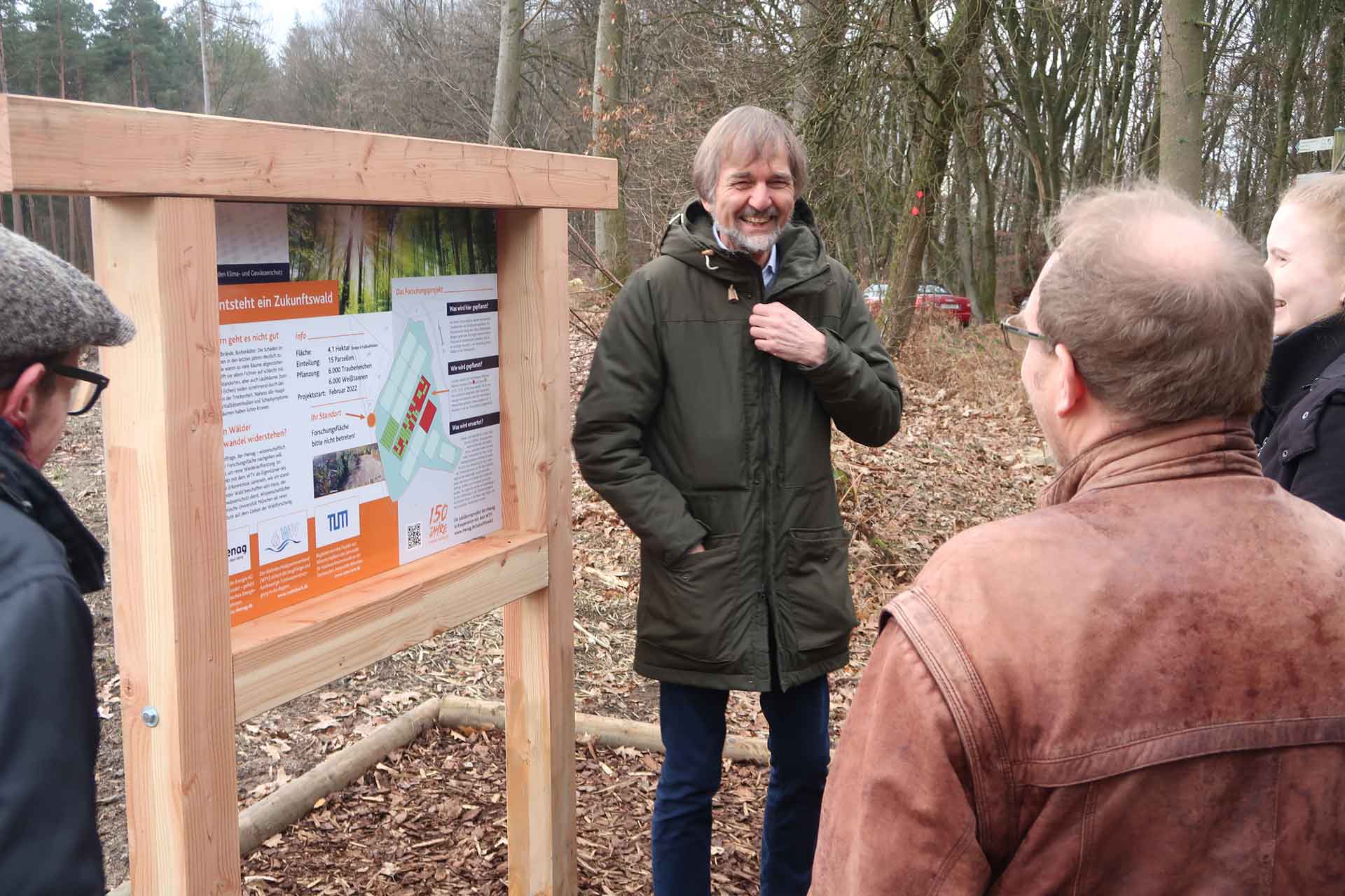 Projektmitarbeiter stehen vor einer Erklärtafel und lachen.