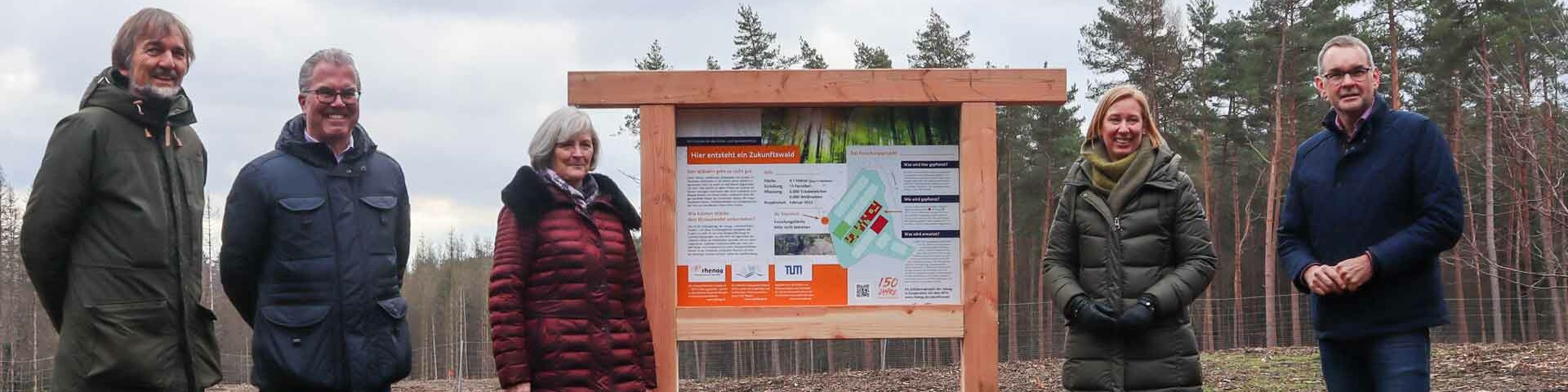 Projektmitglieder stehen neben der Erklärtafel für den Zukunftswald.