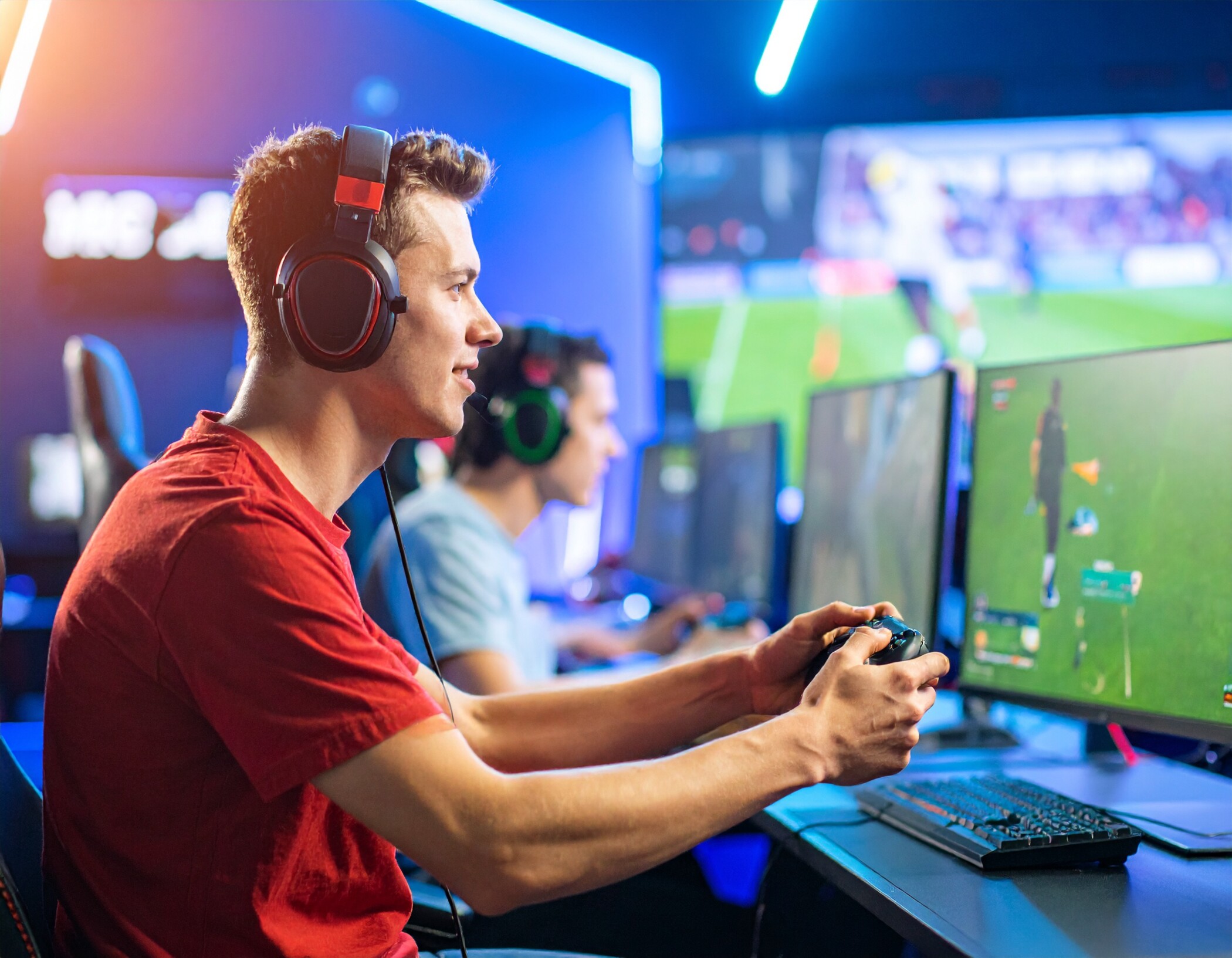Ein junger Mann mit Kopfhörern spielt auf einem eSports-Event mit Controller in der Hand.