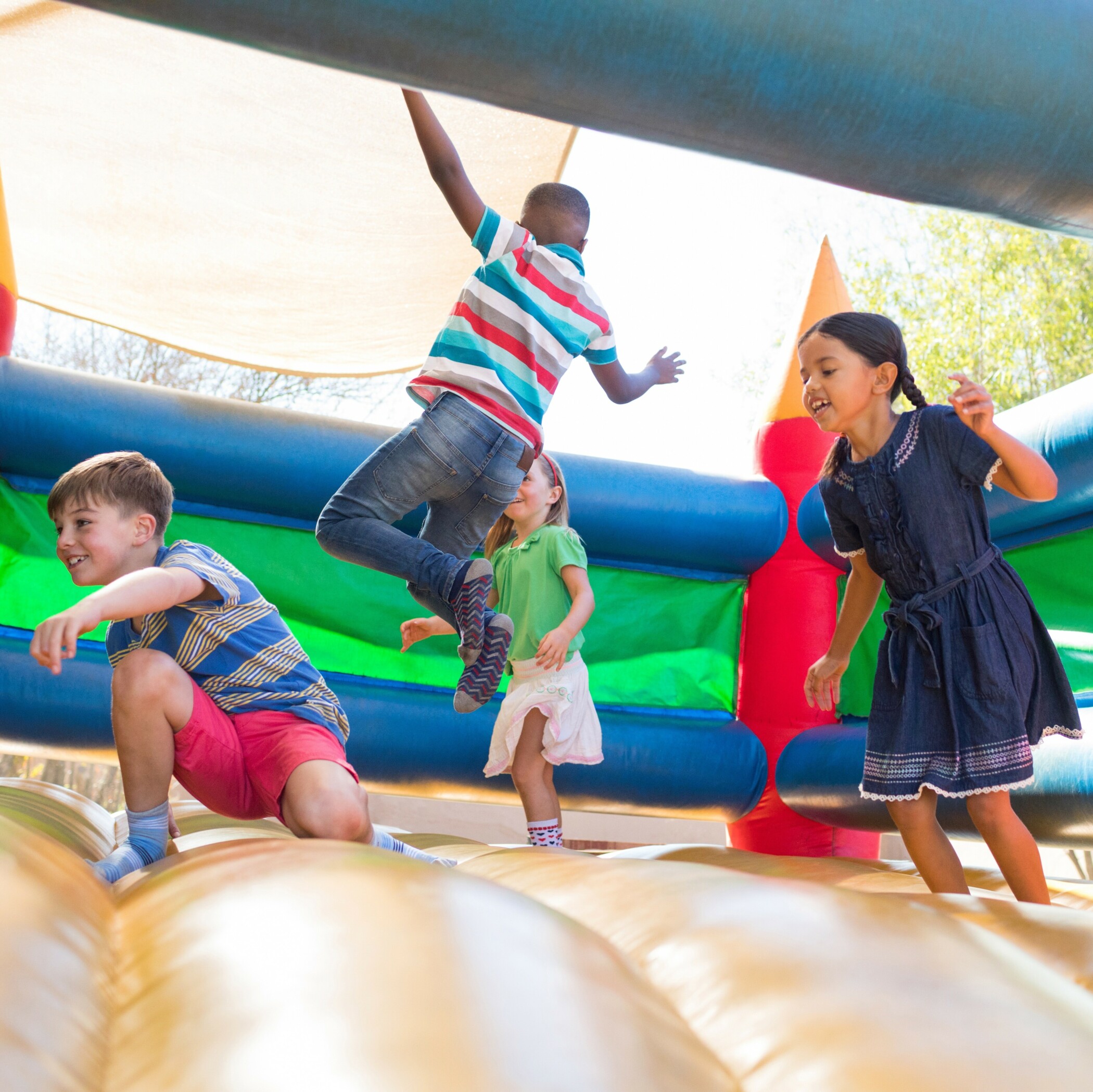 Kinder spielen und hüpfen in einer Hüpfburg.