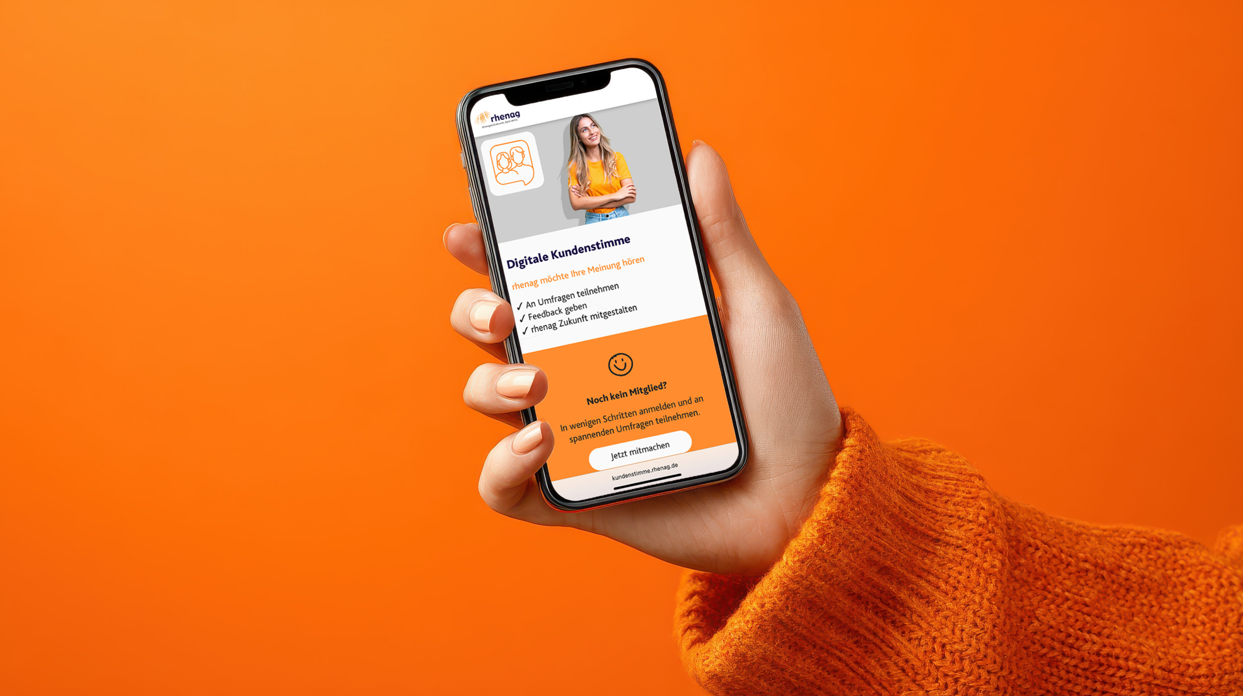 Lächelnde Frau mit rotem Pullover und einer Tasse in der Hand zeigt ihr Handy mit der Website der digitalen Kundenstimme.