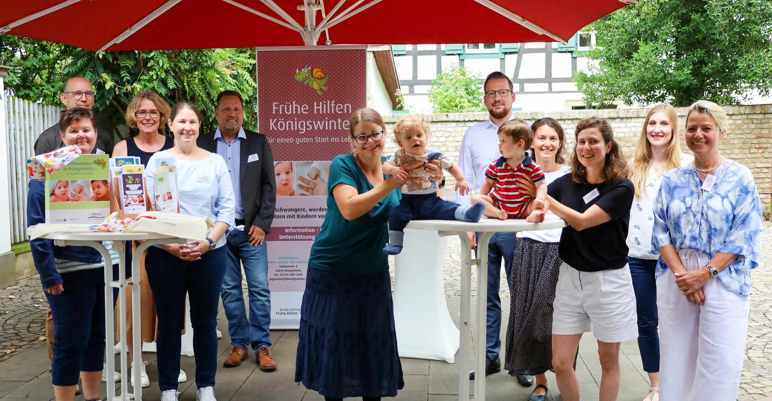 Junge Eltern mit Baby sitzen am Tisch und und die Mutter küsst das Baby auf den Kopf.