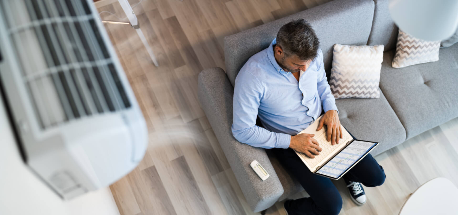 Mann sitzt mit Laptop auf dem Sofa